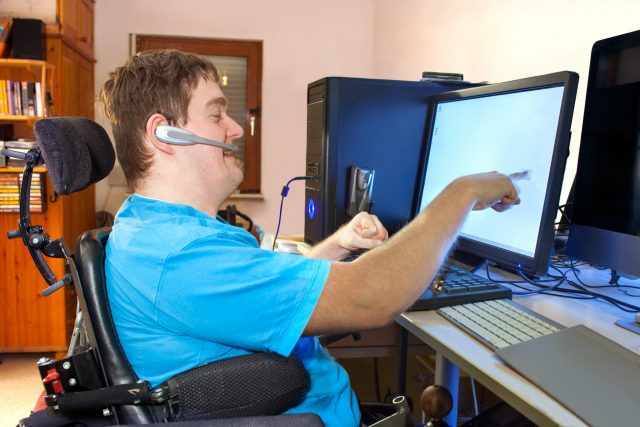 A young disabled man using a touchscreen computer interface