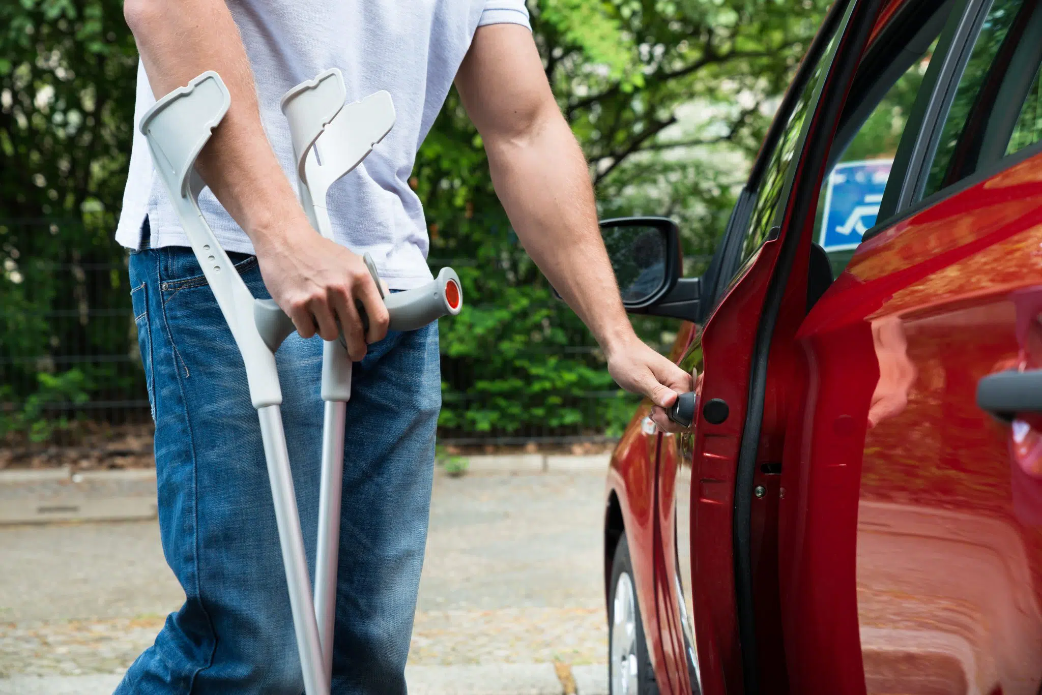 A crippled man using crutches and getting in the car