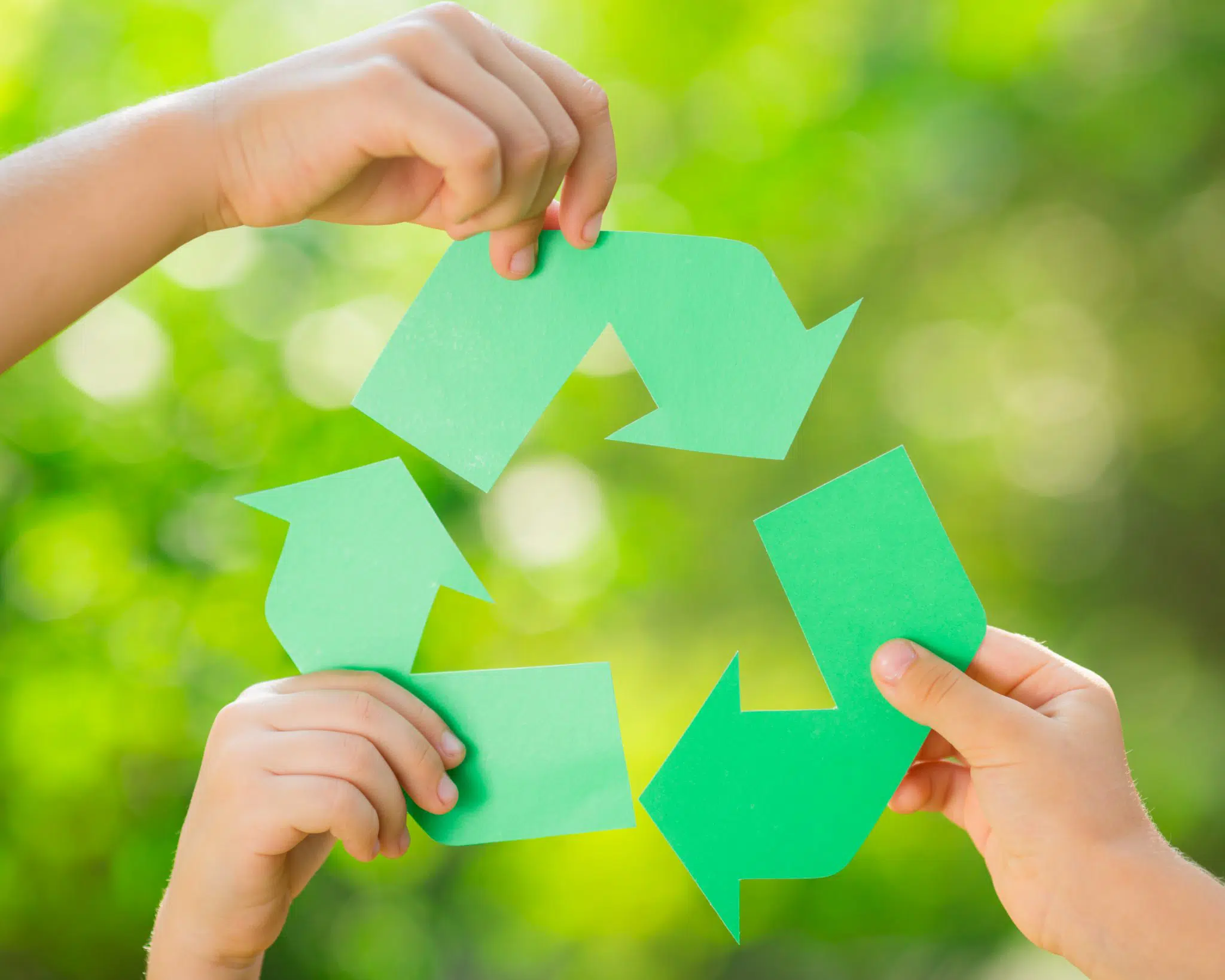 Kids holding recycle symbols.