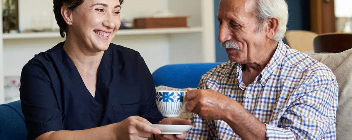 nursing handing man cup of tea