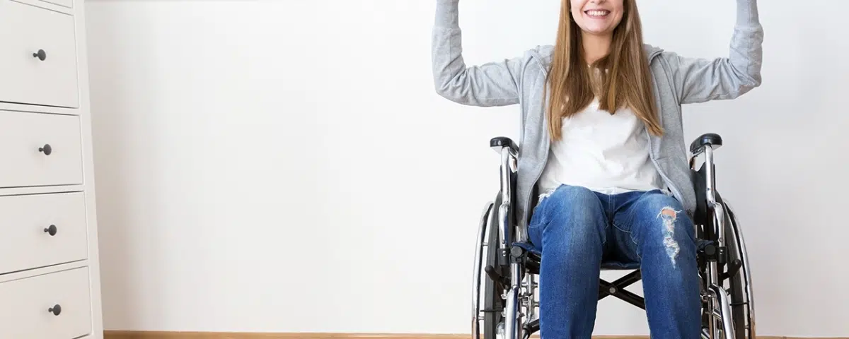 woman seated in wheelchair holding dumbbells above head