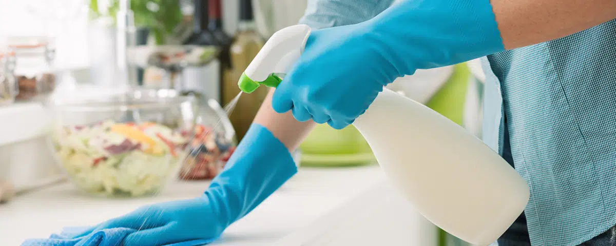 woman spraying countertop with cleaning solution