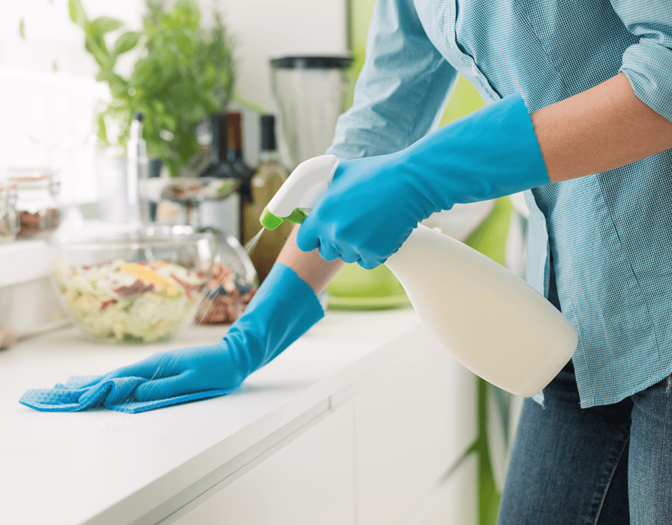 woman spraying countertop with cleaning solution