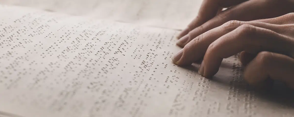 hands reading page of braille