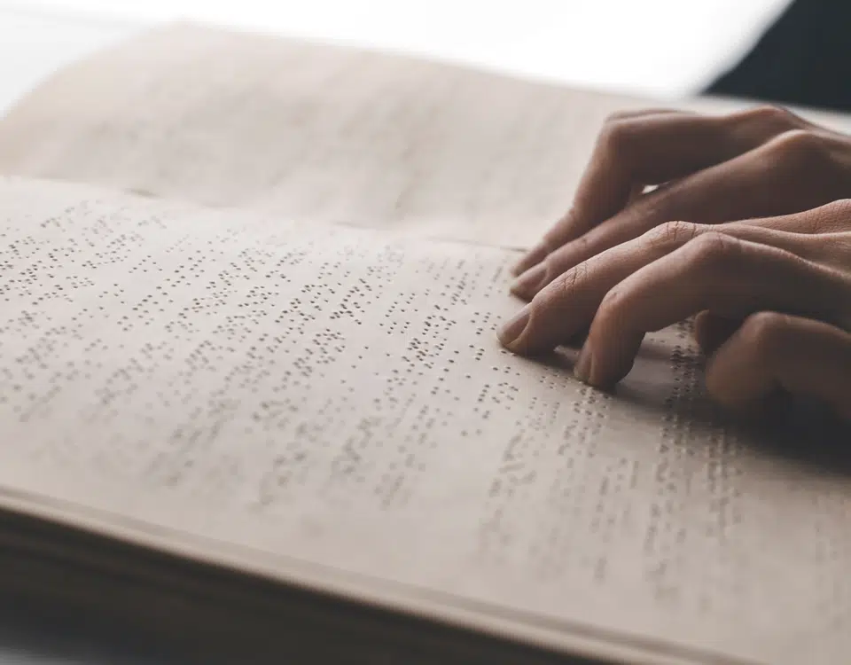 hands reading page of braille