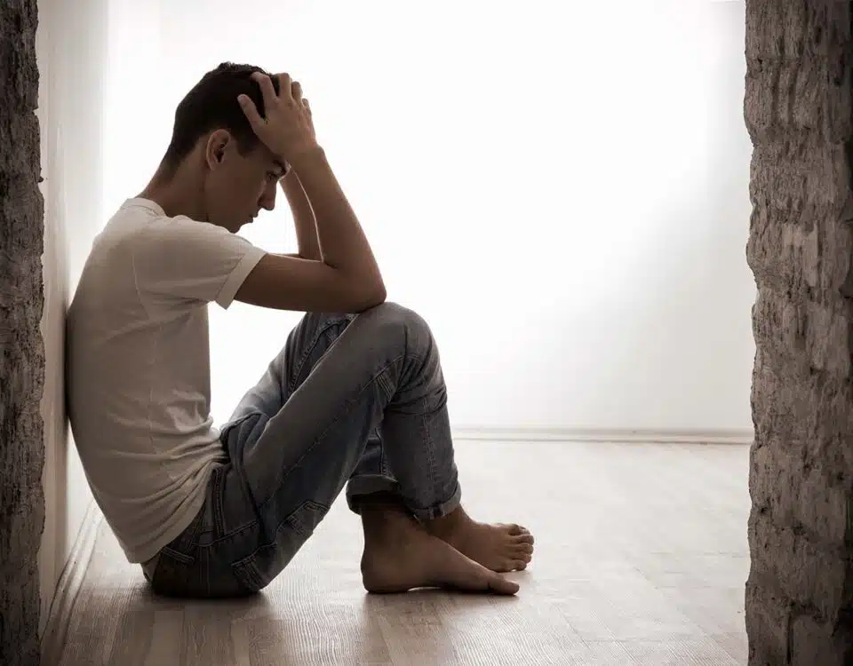 person sitting alone on floor with hands on head