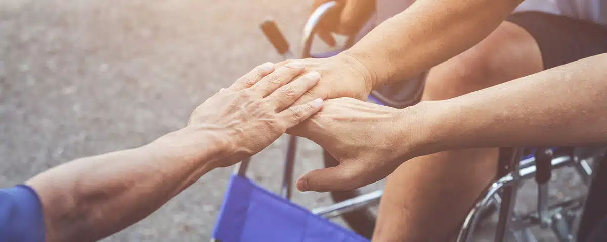 three people in wheelchairs putting their hands together and supporting each other