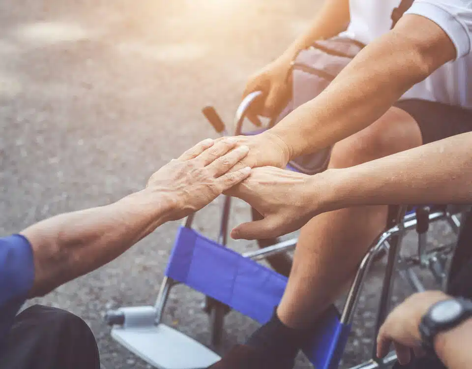three people in wheelchairs putting their hands together and supporting each other