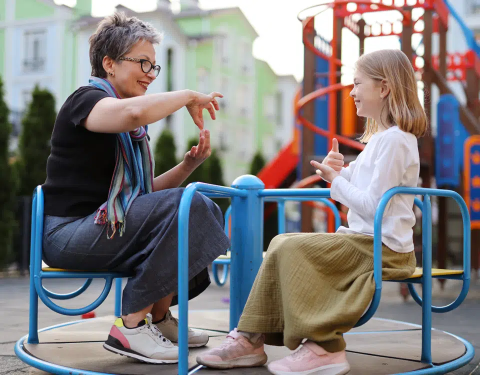 woman signing with deaf child on playground