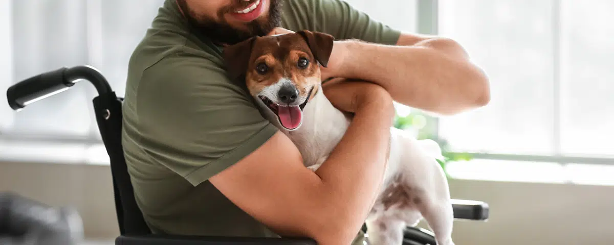 Young veteran in wheelchair with dog at home