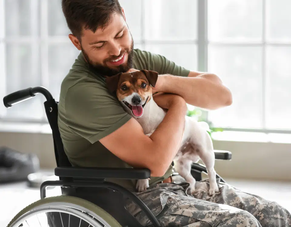 Young veteran in wheelchair with dog at home